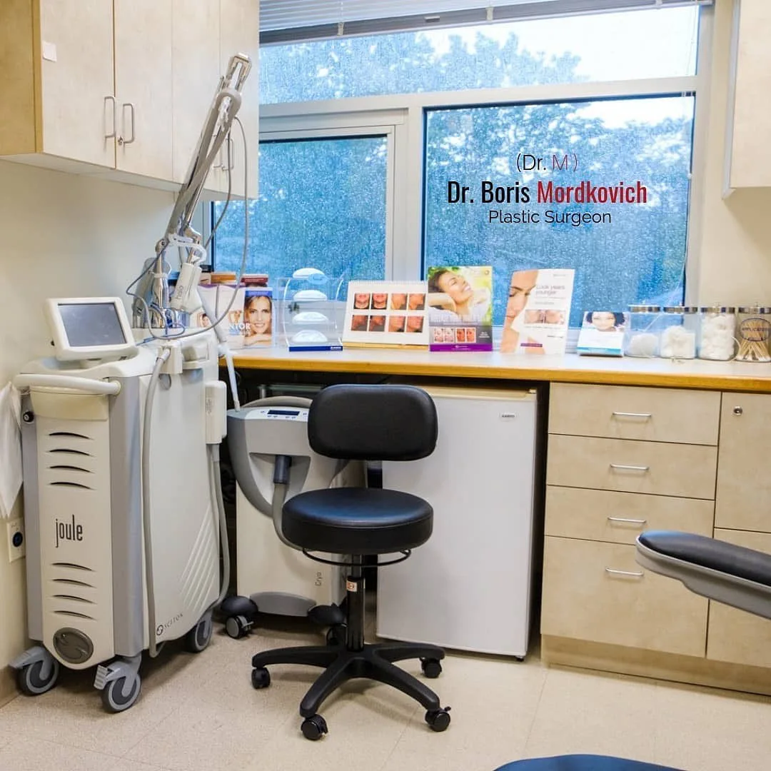 Dr. Boris Mordkovich's consultation room with laser device, treatment photos, and product displays on desk